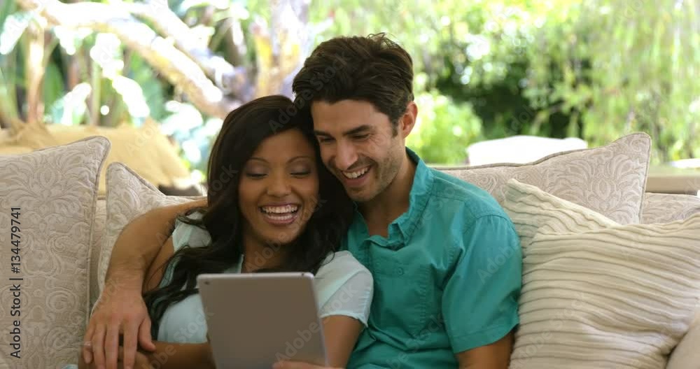 Young couple sitting on sofa and using digital tablet in living room at home Young couple sitting on sofa and using digital tablet in living room at home