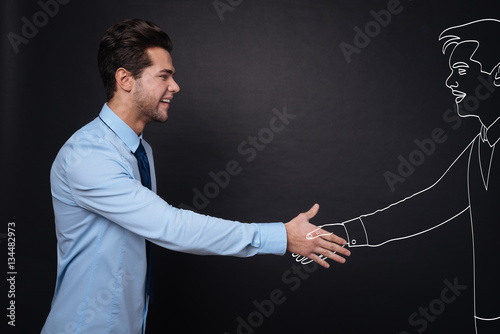 Joyful handsome man shaking hands with work partner.