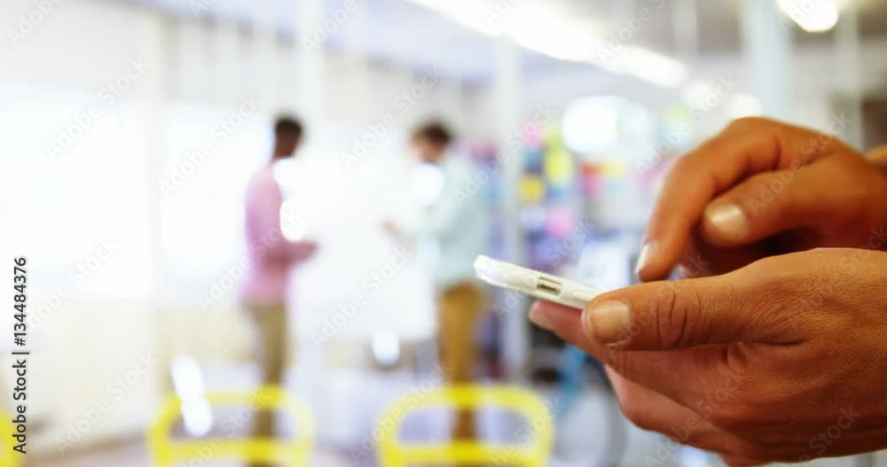 Mid section of male business executive text messaging on mobile phone at office 4k