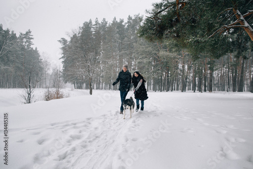 Couple in love have fun with Husky dog in snowy winter cold day