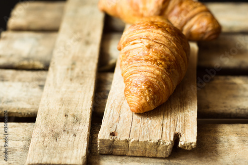 Fresh croissants on aged wood box and plank, close up, golden crust, flaky pastry, rustic vintage style,minimalistic,kinfolk