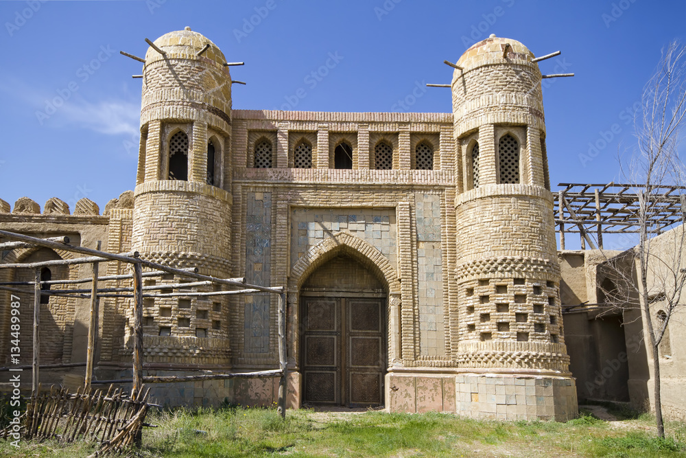 Old castle in Eastern Kazakhstan. Fortress the nomads. Walls and gate of the old fortress made of stone and lined with patterned tiles. Battle towers guarding the fortress. Asia