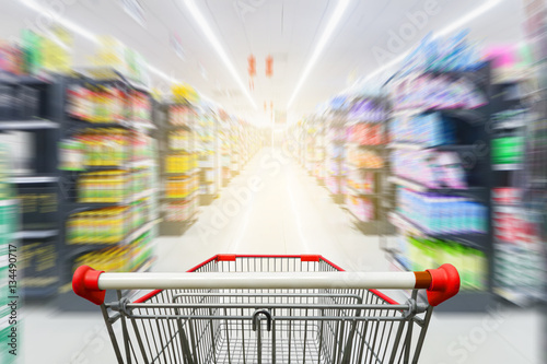 Supermarket aisle with empty red shopping cart photo