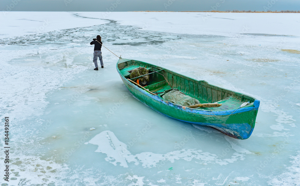Fototapeta premium donmuş gölde teknesini taşıyan balıkçı