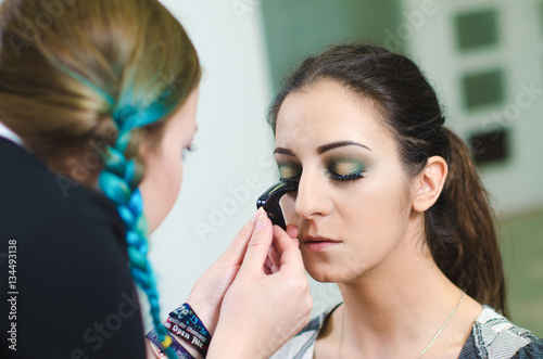 A girl is getting makeup done by a professional.