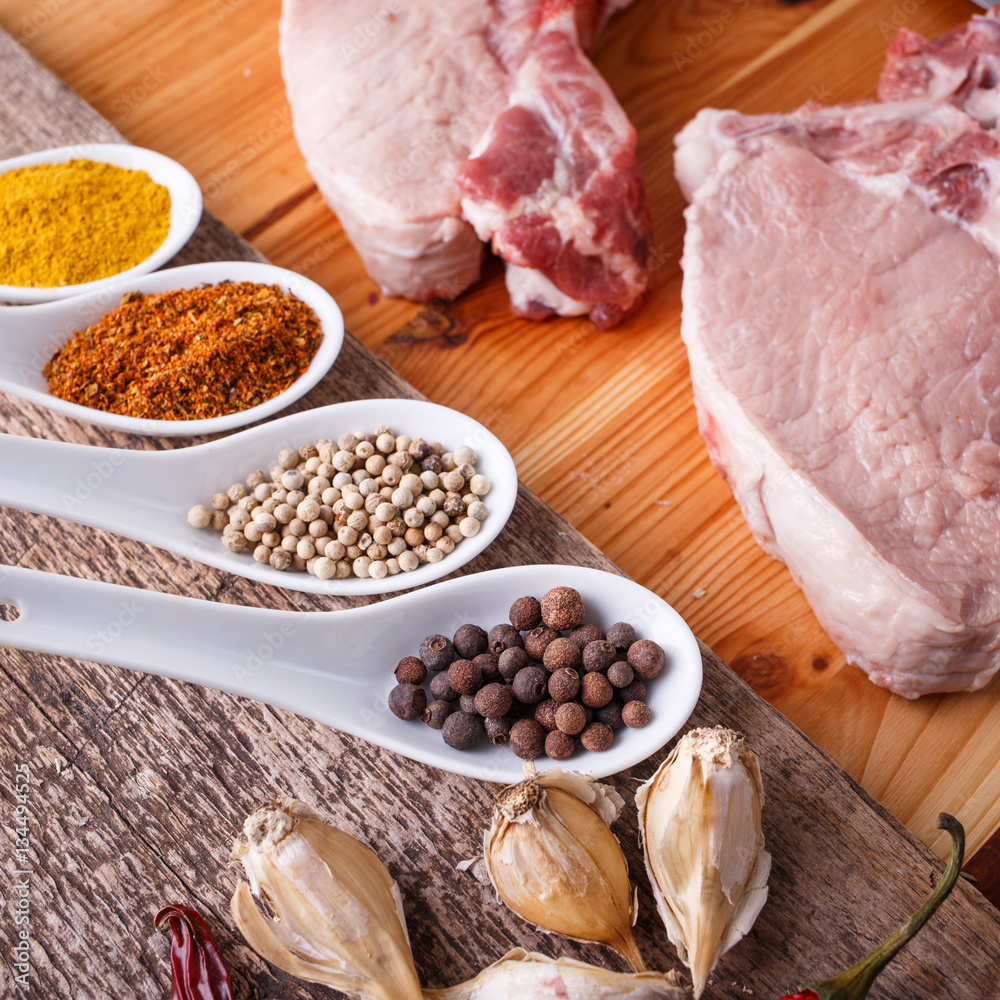 Two fresh raw steaks with spices in a bowl on chopping board