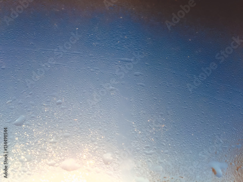 Blurry water drops on sunshine ffrozen window glass background