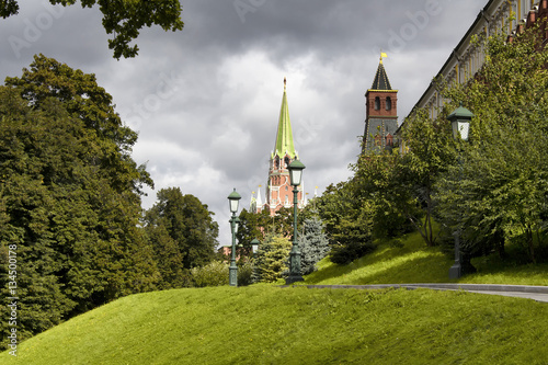 View of Nikolskaya Tower from Alexandrovsky Garden in Moscow. Dark clouds are in the background. Sun light creates dramatic scene on the ground.