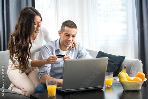Young couple shopping online with credit card and laptop at home. © Bojan