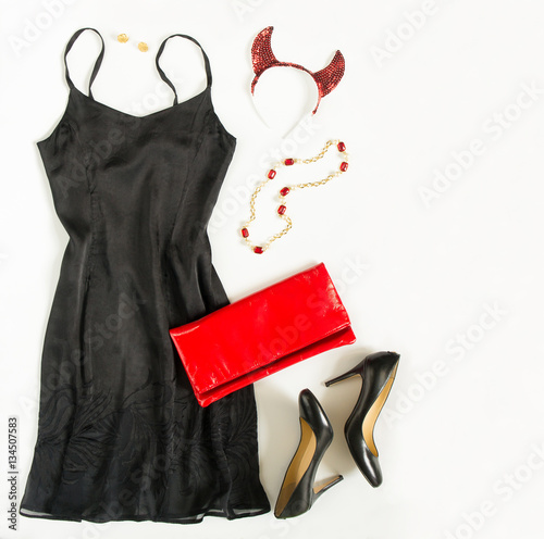 Christmas party outfit. Cocktail dress outfit, night out look on white background. Little black dress, red evening clutch , black shoes, red ang gold necklace and devil horns. Flat lay, top view