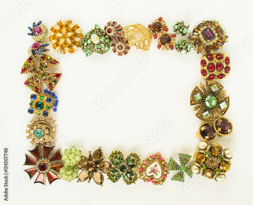 Woman's Jewellery. Frame with old vintage brooches. Beautiful bright rhinestones brooches on white. Flat lay, top view