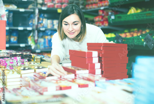 attractive girl customer looking for tasty sweets in supermarket