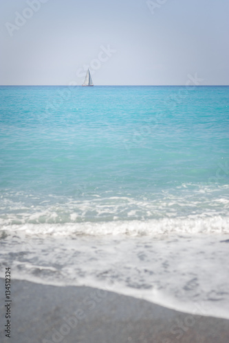 Seascape. The coast of the Ligurian Sea, with turquoise water. Sailboat on the horizon.