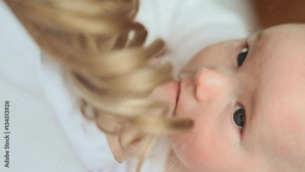 Mother has blond hair. Baby feeds on mom's breasts. Mother has blond hair. Baby feeds on mom's breasts.