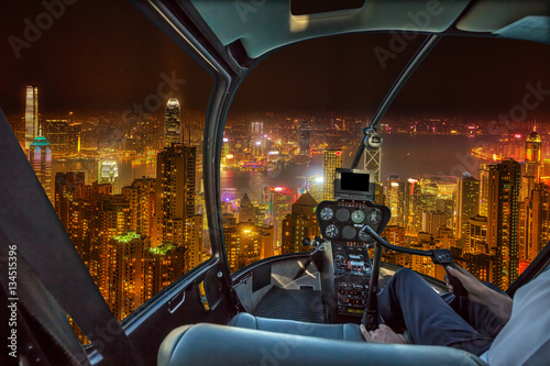 Aerial view inside helicopter cockpit night flight on Hong Kong cityscape in the night in Wan Chai district, Hong Kong island. Concept of transport, travel and business.