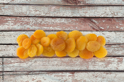 Heap of dried apricots on wooden background. Dried fruit at border of image with copy space for text. Top view.