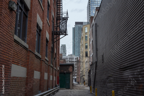 Picture of a dilapidated impasse street with the skyscraper skyline of Toronto in the background