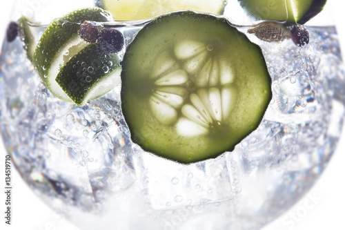 Glass of gin tonic with ice, cucumber and lime and white background