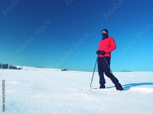 Tourist with snowshoes walk in snowy drift. Sunny freeze weather.