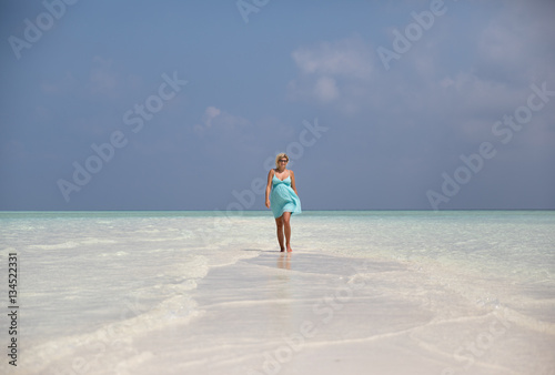 Beautiful pregnant woman is walking on sand bank, Maldives