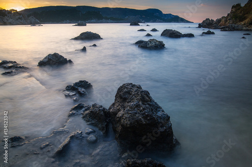 Long exposure seascape at sunrise. View of the cliff into the sea and distant islands. Paleokastrica. Corfu. Ionian archipelago. Greece.