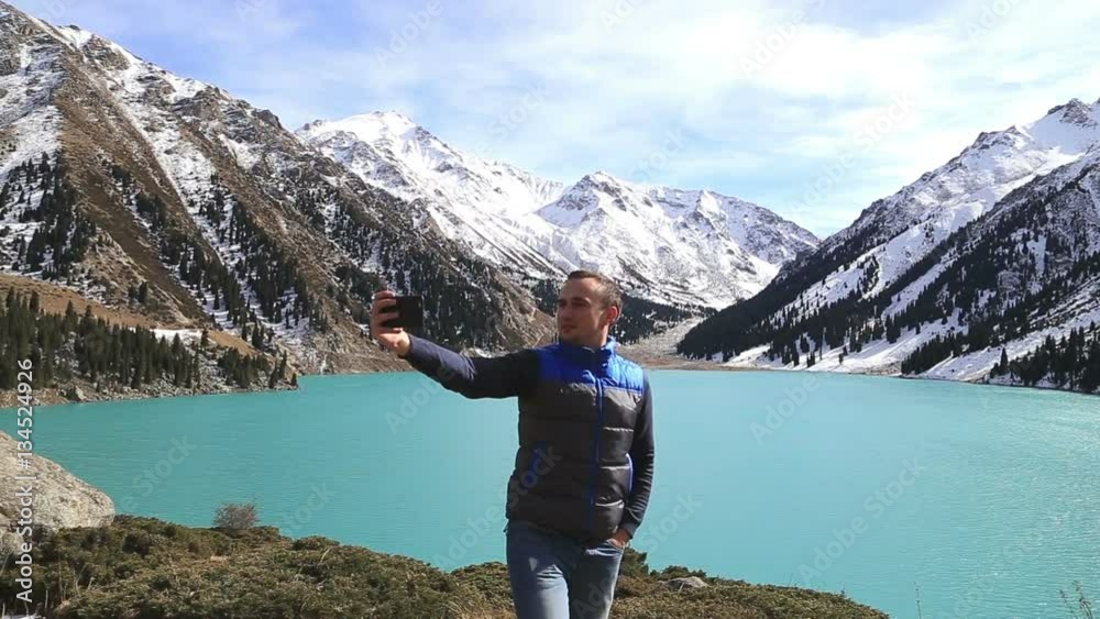 young successful white caucasian man make selfie on the background of amazing beautiful mountain lake landscape young successful white caucasian man make selfie on the background of amazing beautiful mountain lake landscape