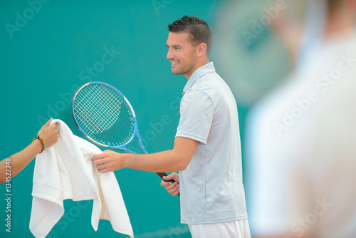 Tennis player being passed a towel © auremar