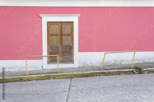 Wood colonial style windown and pink wall facing empty street