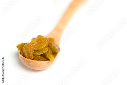 A driend raisin in a wooden spoon isolated over white background photo