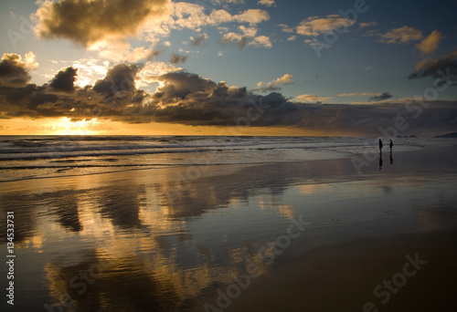 People walking along the Oregon coast at sunset