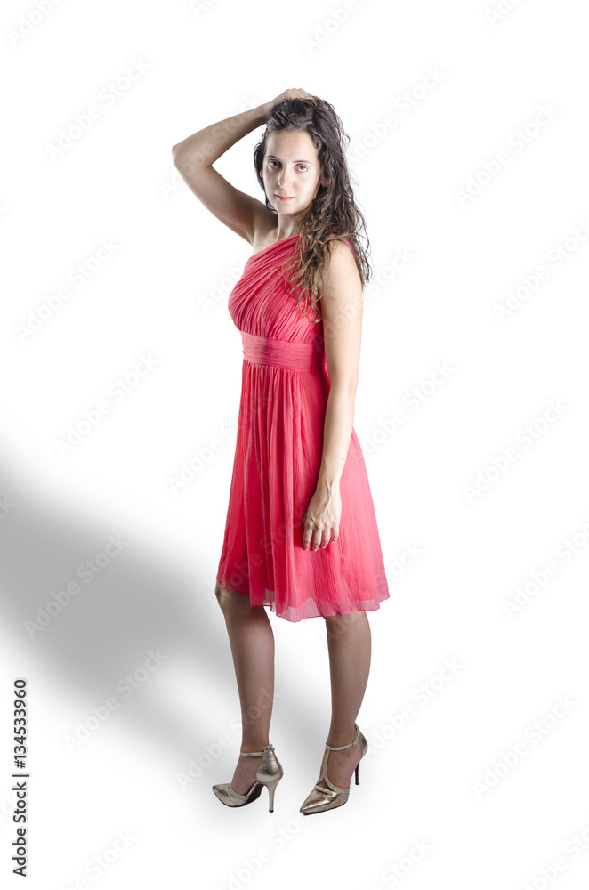 Young woman standing wearing a coral dress and gold high heels Young woman standing wearing a coral dress and gold high heels