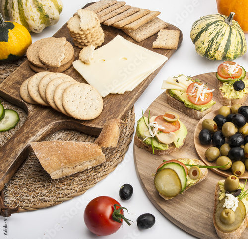 Sandwiches, cheese, crackers and vegetables on wooden boards on