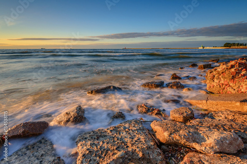Blurred waves on the rocky beach. Baltic Sea at sunset light. Poland.