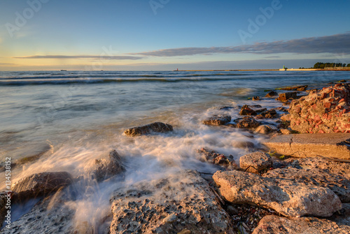 Blurred waves on the rocky beach. Baltic Sea at sunset light. Poland.