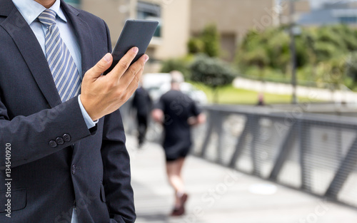 isolated business man hold the smartphone on the street 