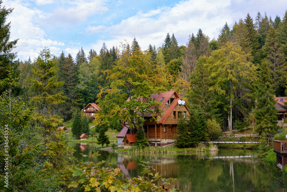 House near the lake in the forest, autumn day.