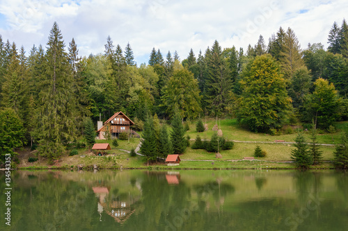 House near the lake in the forest, autumn day.