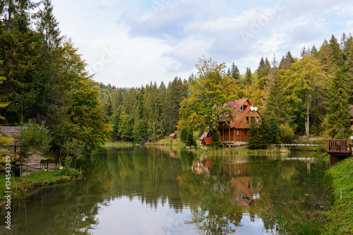 House near the lake in the forest, autumn day.