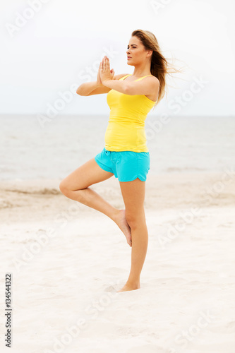 Young woman making yoga exercises on the beach © Piotr Marcinski