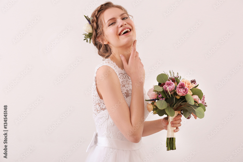 Young beautiful bride holding wedding bouquet on white background
