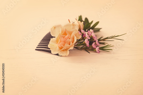 Bridal comb decorated with fresh flowers on white wooden table