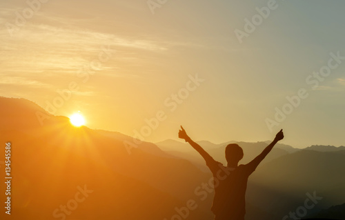Man Silhouette Raised Up hands at Mountain with Sunrise in Morni