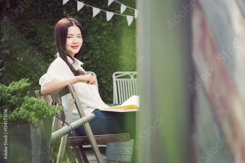 young happy asian woman smiling at camera holding a book
