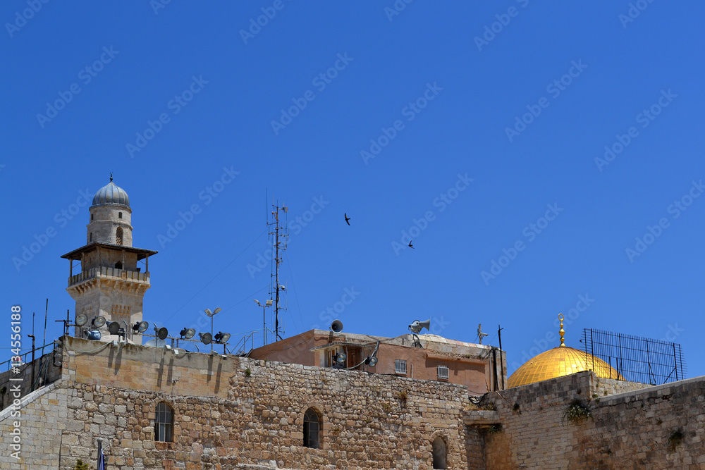 Roofs of churches and the minarets of Jerusalem in the old city on the background of blue sky with two soaring birds