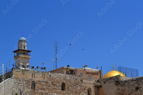 Roofs of churches and the minarets of Jerusalem in the old city on the background of blue sky with two soaring birds