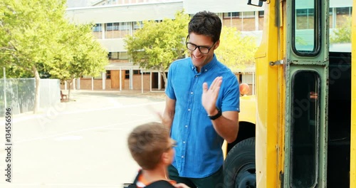 School kids giving high five to teacher while entering the bus at campus 4k