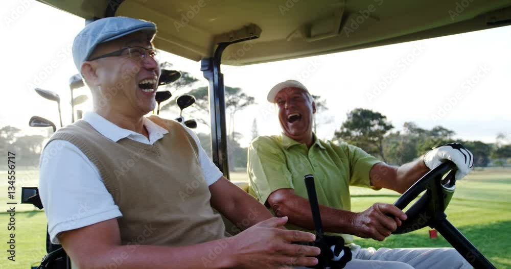 Two golfers laughing together in their golf buggy at golf course