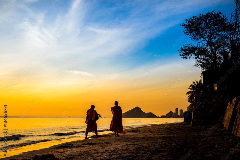 Buddhist monks walk collecting alms, morning beach.