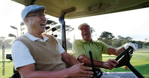 Two golfers laughing together in their golf buggy at golf course