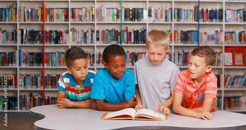 School kids reading book together in library at elementary school 4k